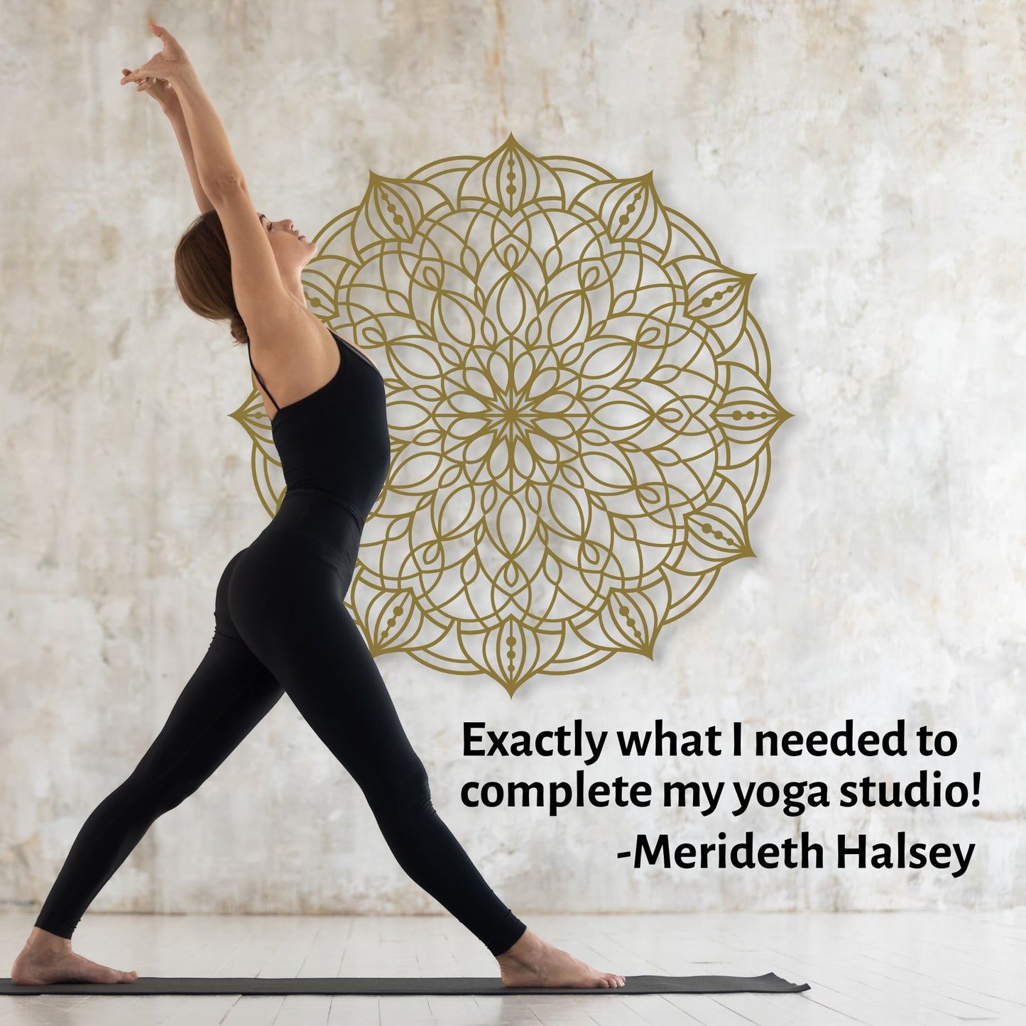 Woman in black yoga attire performing a pose with a gold mandala on a textured wall.