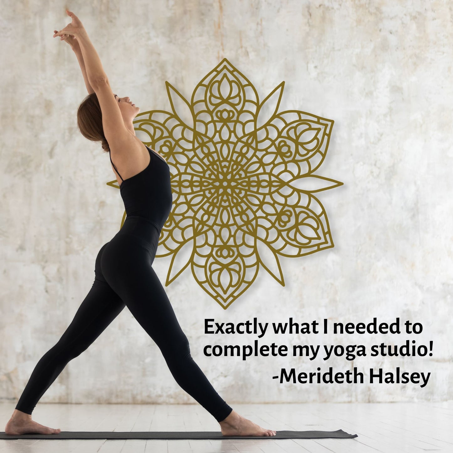 Woman in black yoga attire performing a pose with a decorative gold mandala on a textured wall.