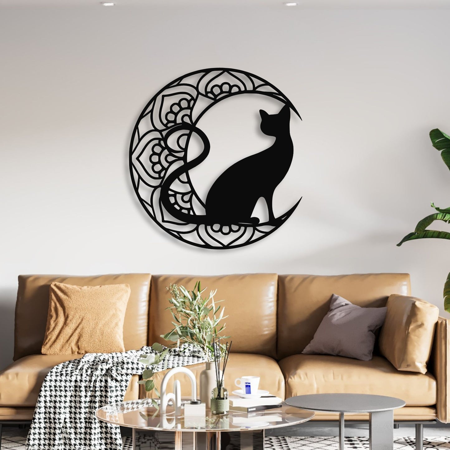 Decorative wall art of a black cat silhouette in a circular design on a white wall above a brown sofa.