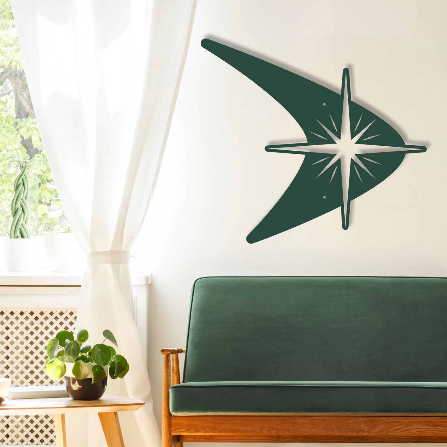 Green wall art in the shape of a stylized star on a white wall above a green sofa.