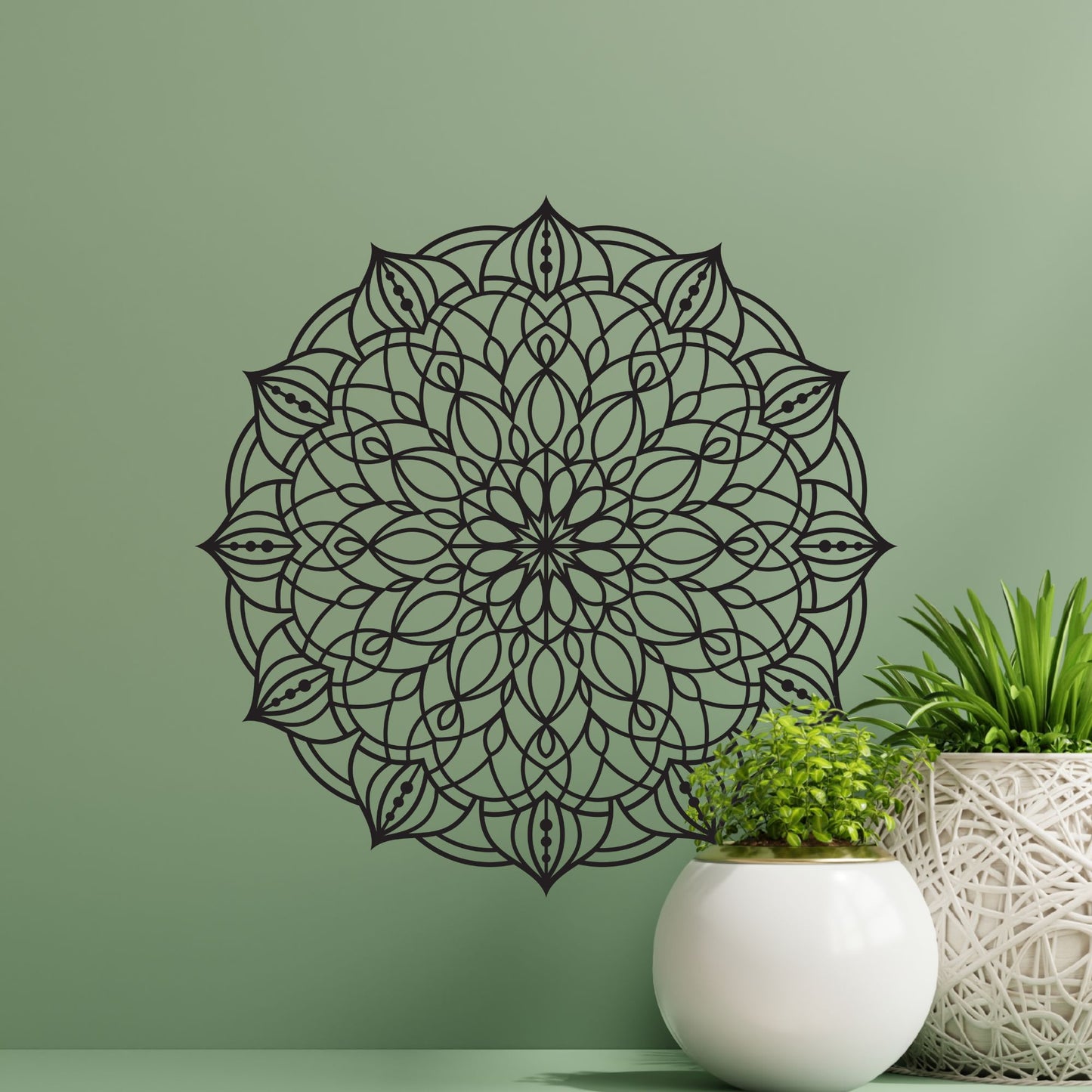 Decorative black mandala wall decal on a green wall with potted plants.