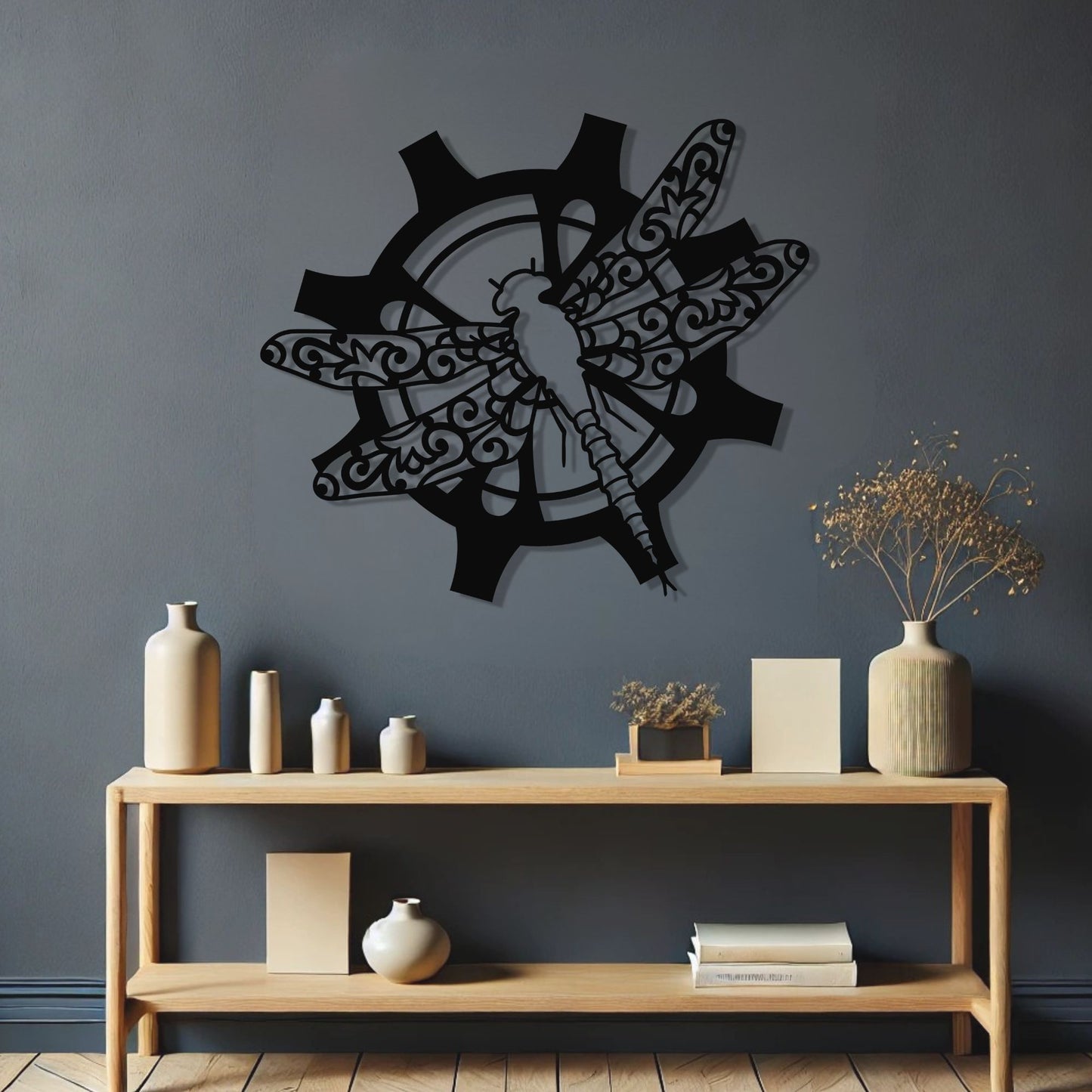 Decorative wall art of a dragonfly on a dark wall above a wooden console table with decorative items.