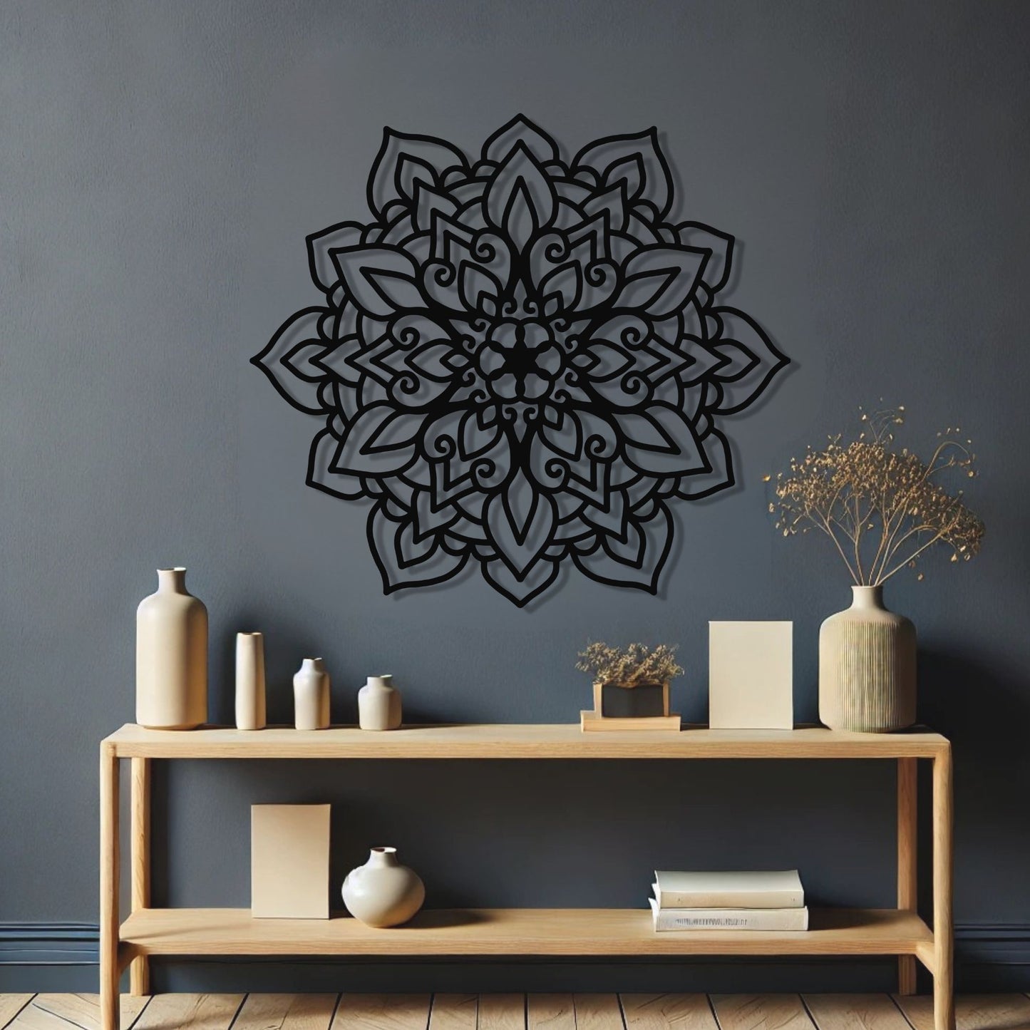 Decorative black mandala wall art on a gray wall with a wooden shelf below containing various items.