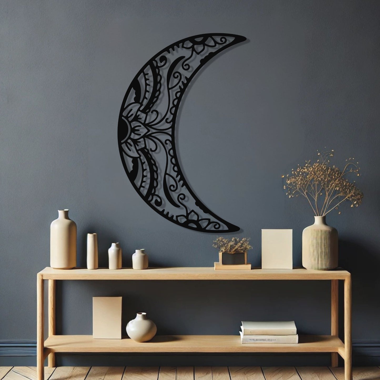 Decorative metal crescent moon wall art on a dark gray wall with a wooden console table below.