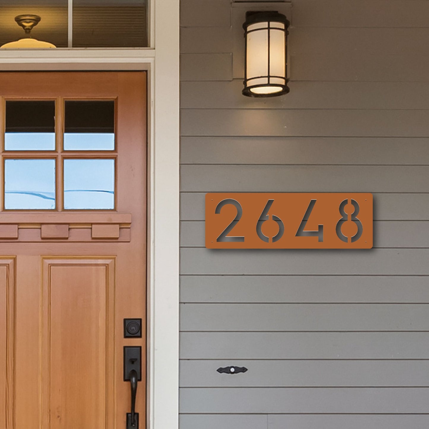 Horizontal Number Address Sign, Closed Style in copper shown next to cedar wood door on grey siding