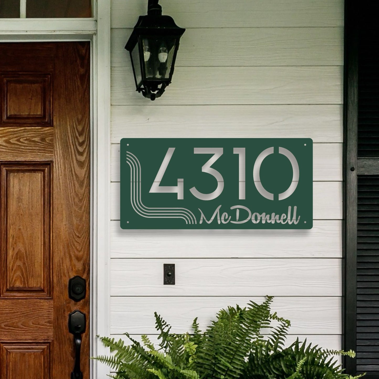House number sign with '4310 McDonnell' on a white wall above a wooden door.