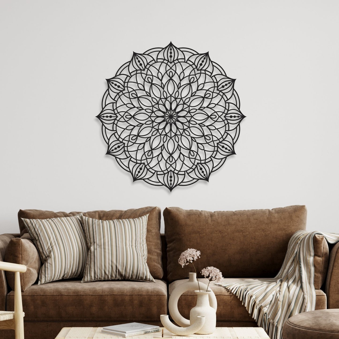 Decorative black mandala wall art on a white wall above a brown sofa with striped cushions.