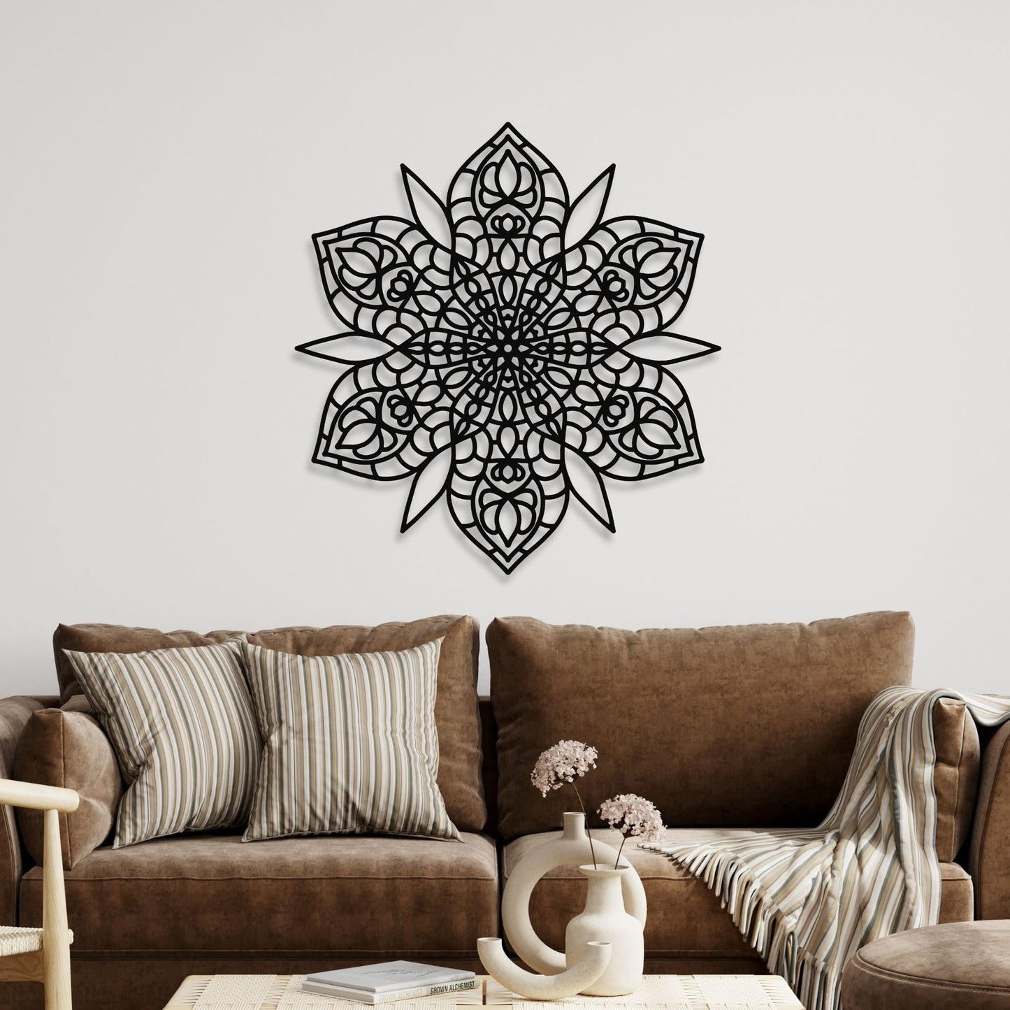 Decorative black mandala wall art on a white wall above a brown sofa.