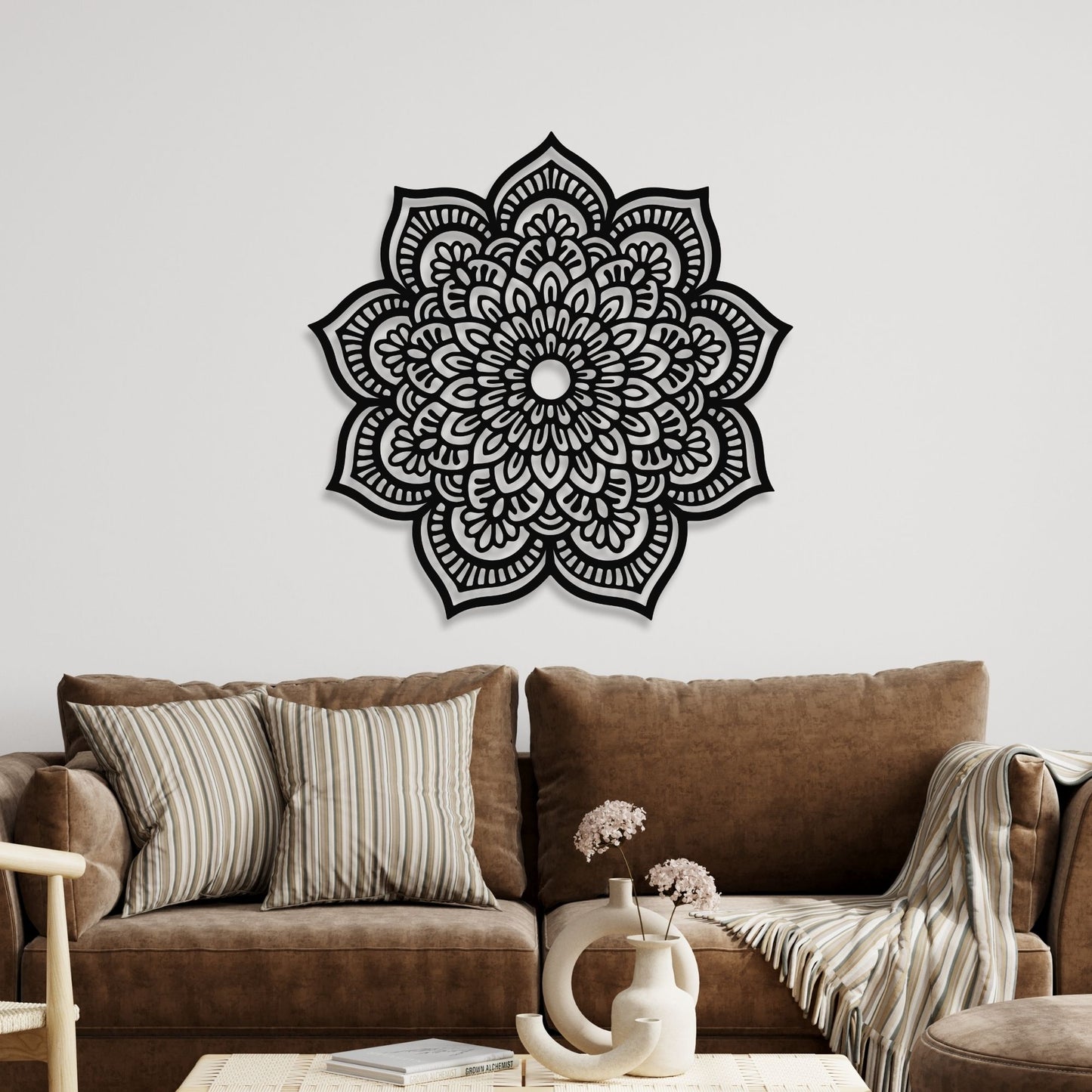 Decorative black mandala wall art on a white wall above a brown sofa.