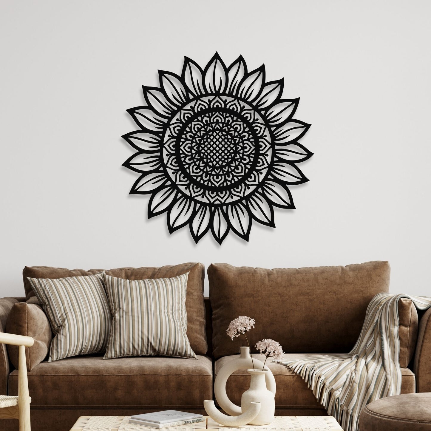 Black mandala wall decor on a white wall above a brown sofa.