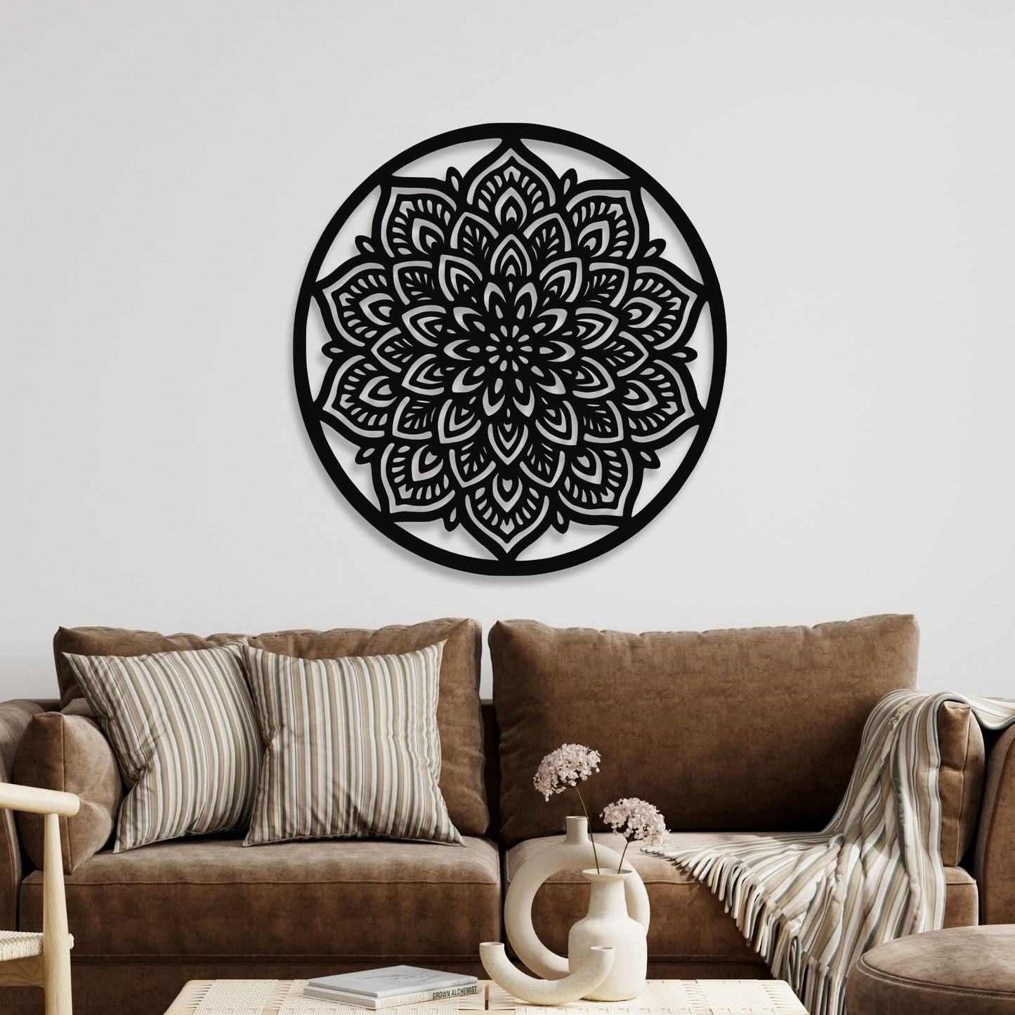 Decorative black mandala wall art on a white wall above a brown sofa.