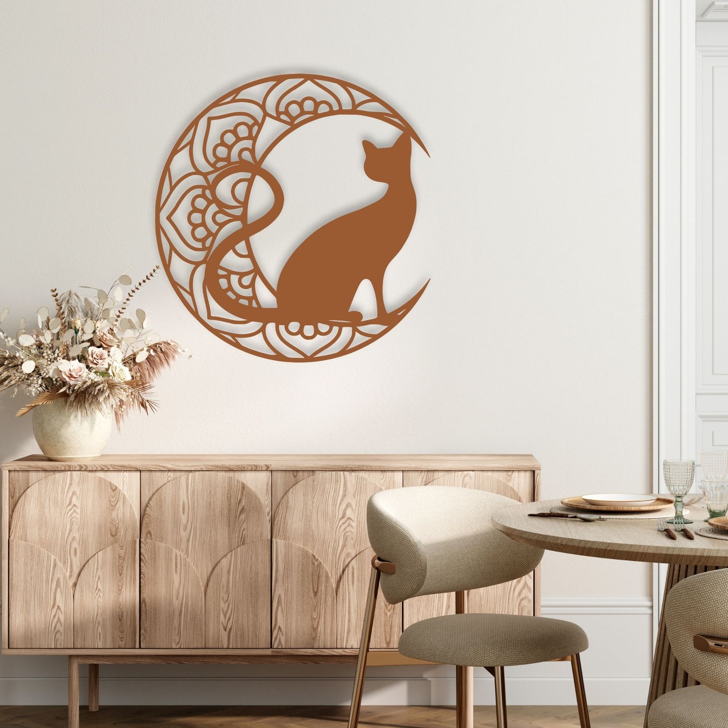 Decorative wall art of a cat silhouette in a circular design on a white wall above a wooden cabinet.