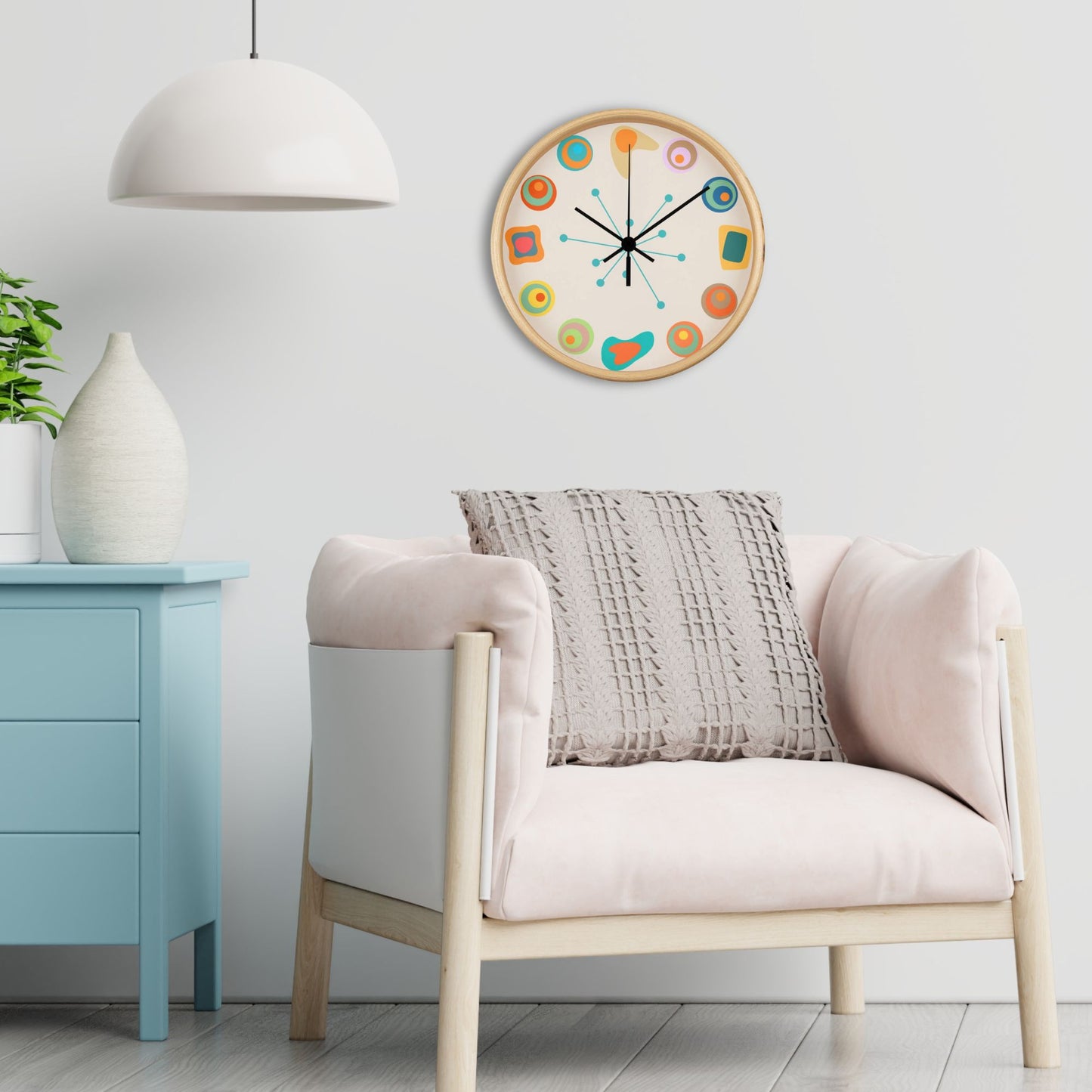 Decorative wall clock on a white wall above a light-colored armchair with a gray pillow.