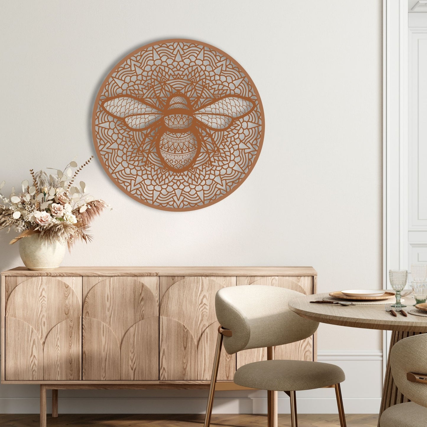Decorative wall art of a bee on a white wall above a wooden cabinet.