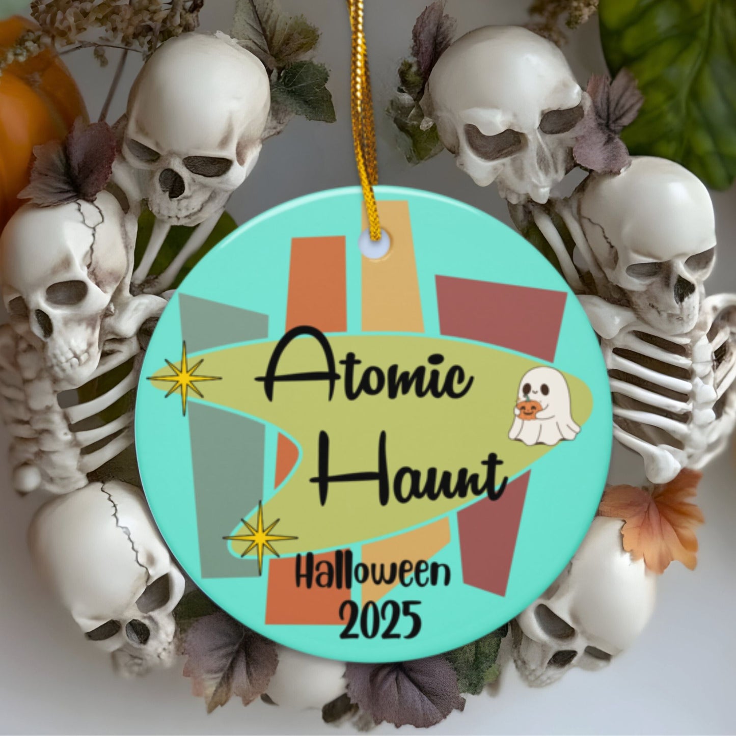 Halloween ornament with 'Atomic Haunt Halloween 2025' text surrounded by skeletons and pumpkins.