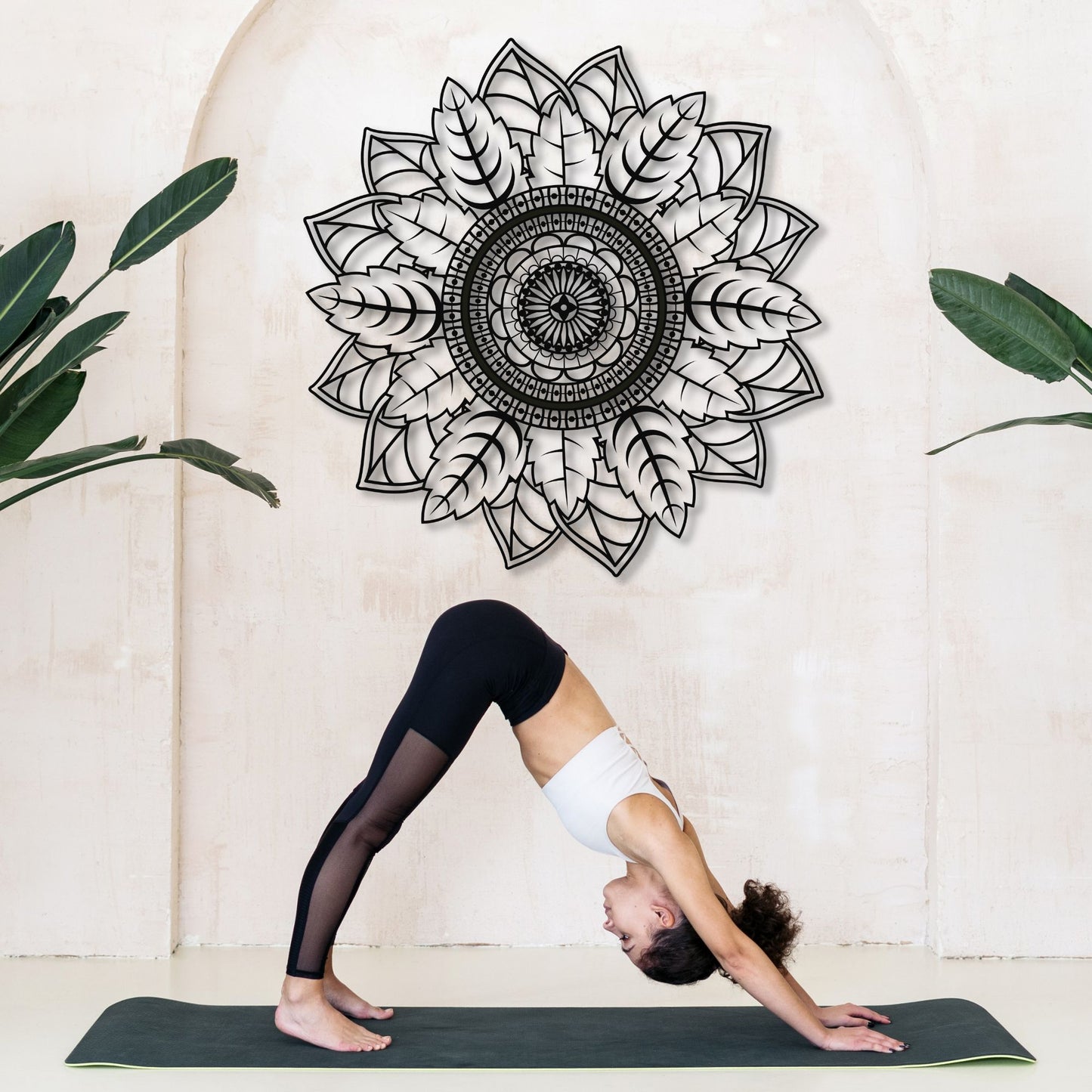 Person in a yoga pose on a mat with a decorative mandala wall art in the background.