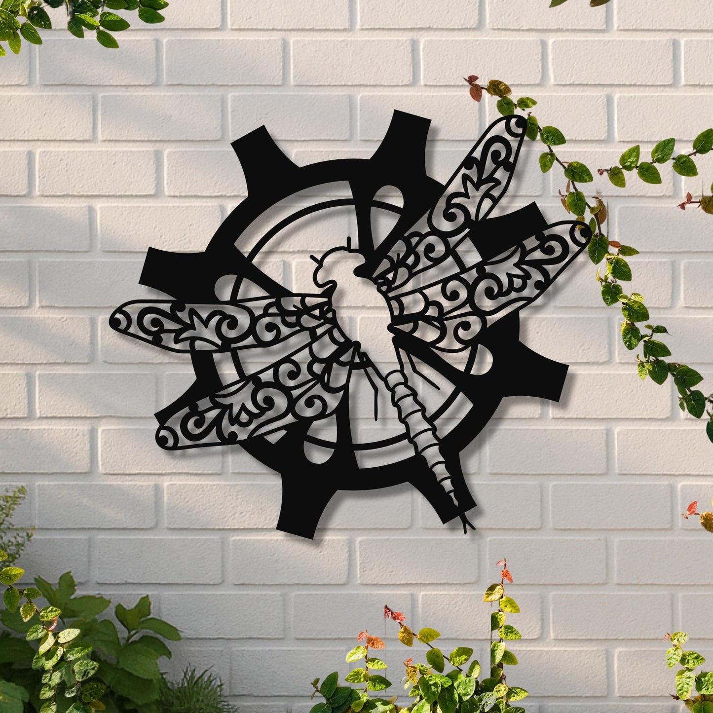 Decorative metal wall art of a bird and gears on a white brick wall with greenery.