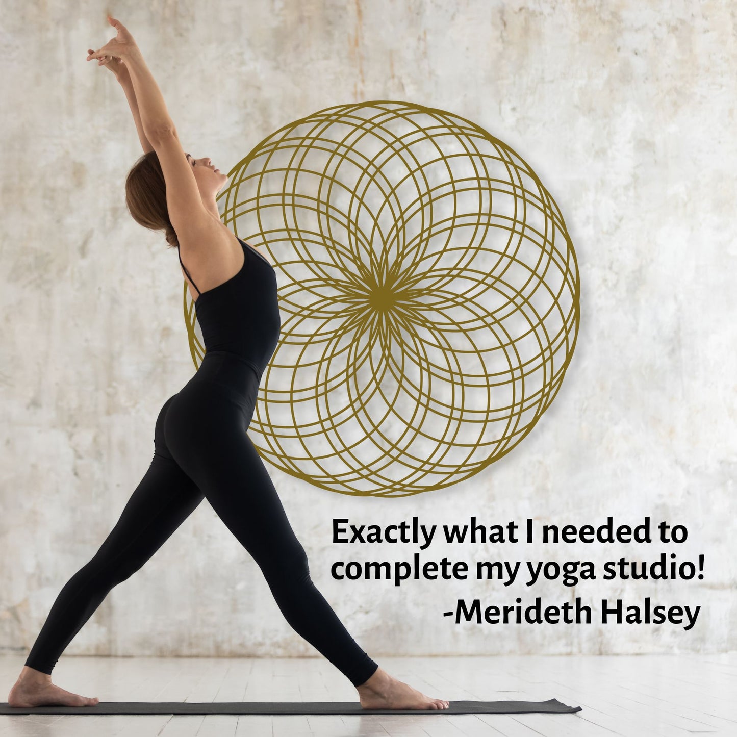 Woman in black yoga attire practicing yoga in a studio with a decorative wall piece.