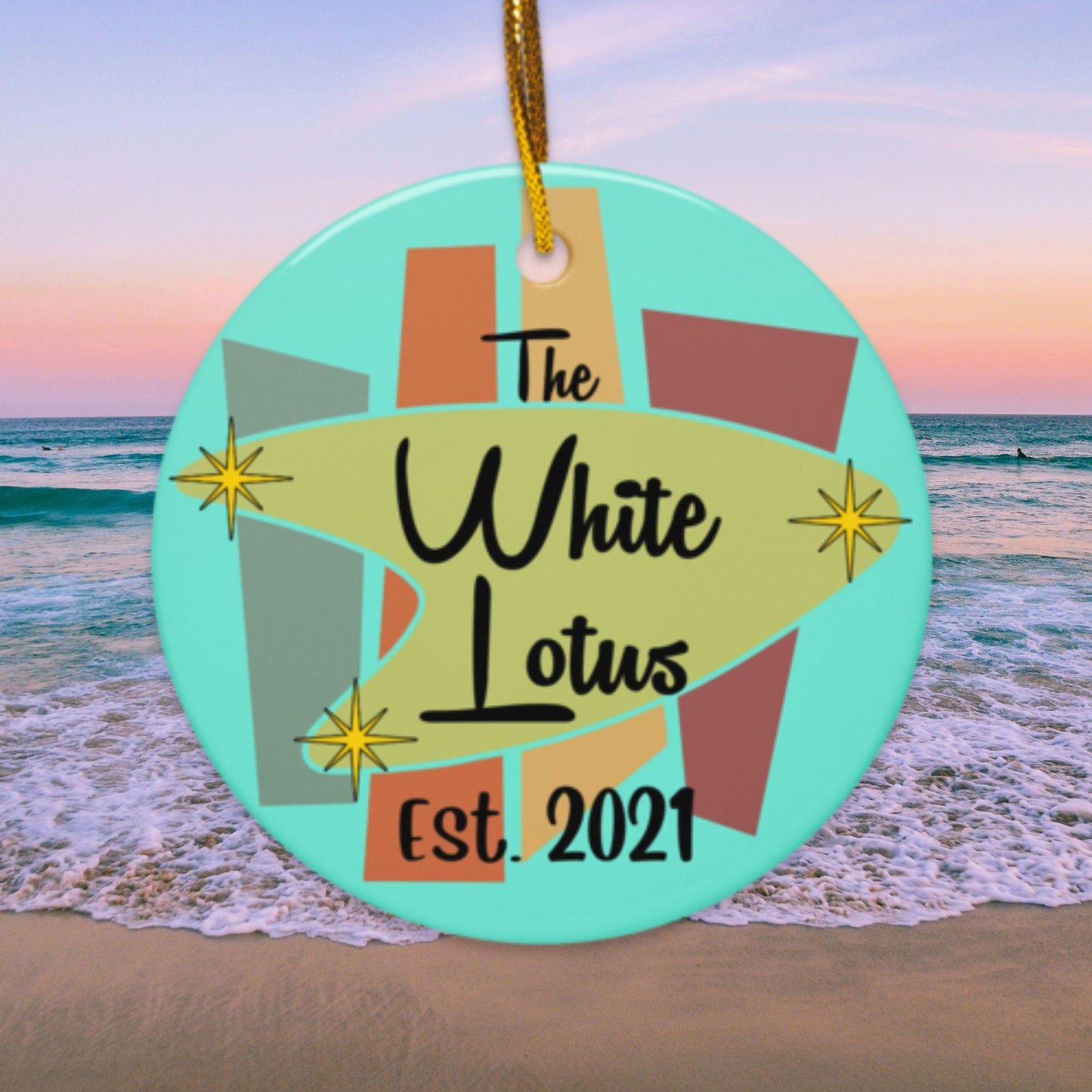 Circular ornament with 'The White Lotus' design against a beach background