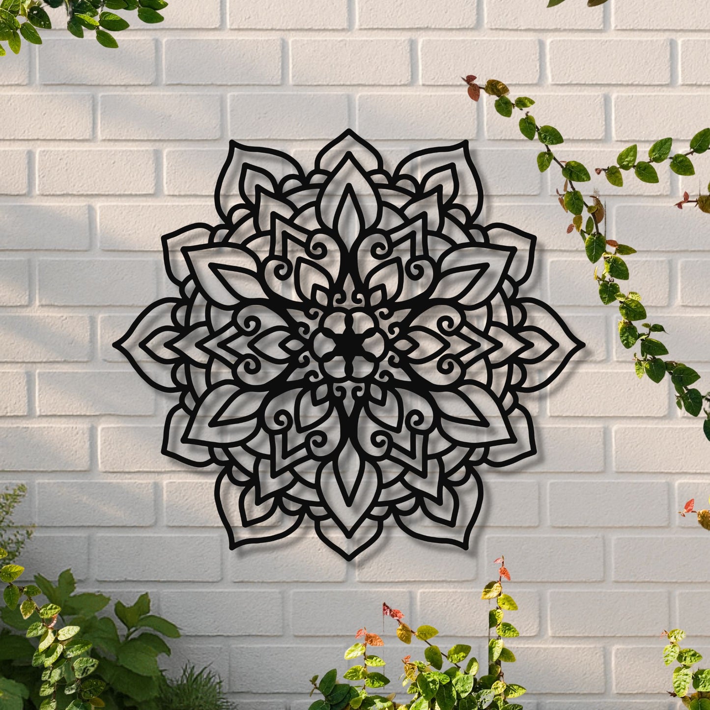 Decorative metal wall art with a floral pattern on a white brick wall.