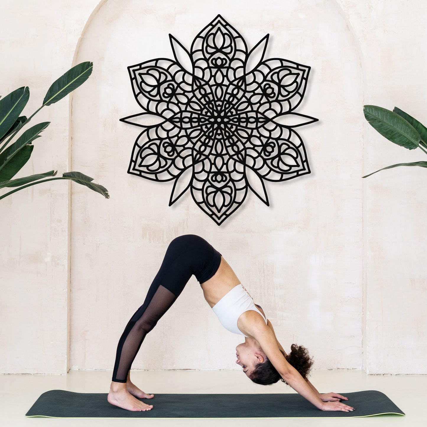 Person in a yoga pose on a mat with a decorative wall piece in the background
