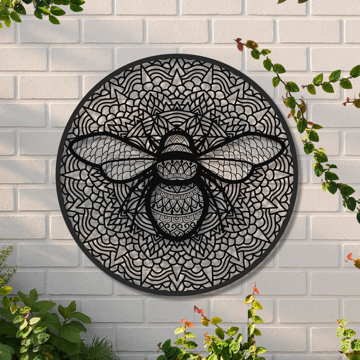 Decorative wall art of a bee with intricate patterns on a white brick wall.