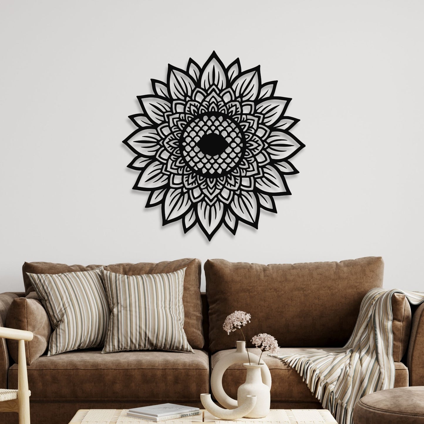 Decorative black mandala wall art on a white wall above a brown sofa.