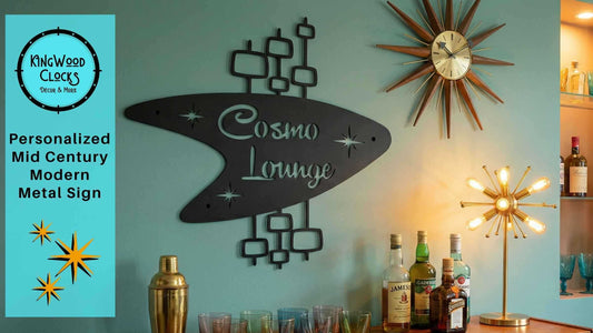 Mid Century Modern Boomerang Metal Sign reading Cosmo Lounge mounted above a retro home bar with starburst clock, brass lamp, and colorful cocktail glasses in teal and gold tones.