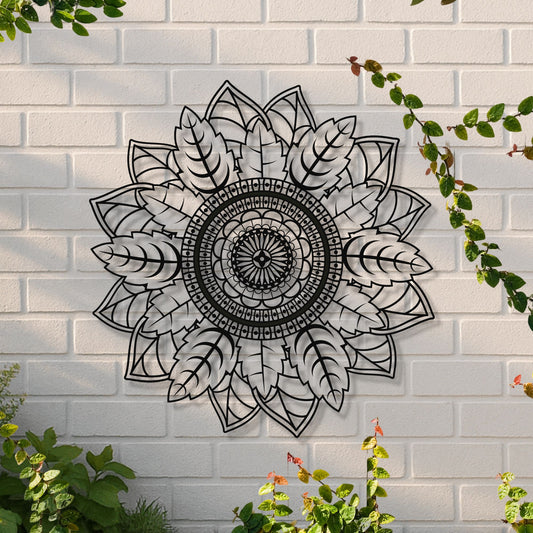 Decorative black mandala wall art on a white brick wall with greenery.