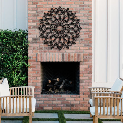 Brick fireplace with decorative metal wall art, outdoor chairs, and greenery.