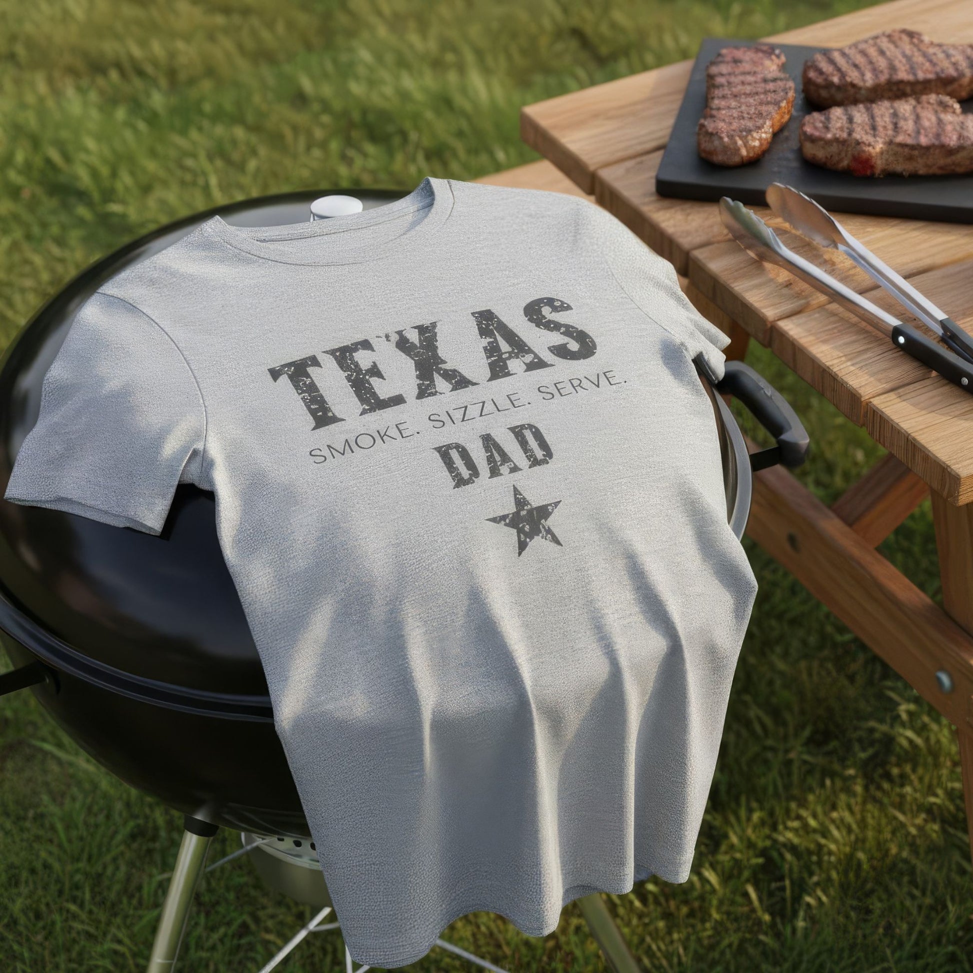 T-shirt with 'Texas Dad' text on a grill outdoors