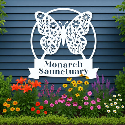 Decorative metal butterfly sign with 'Monarch Sanctuary' text, surrounded by colorful flowers against a blue wooden background.