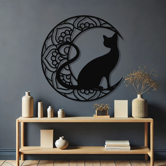 Decorative wall art of a black cat silhouette on a moon with a wooden console table below.