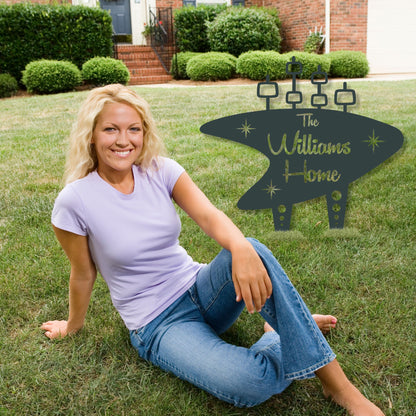 Woman sitting on grass with a personalized home sign in the background