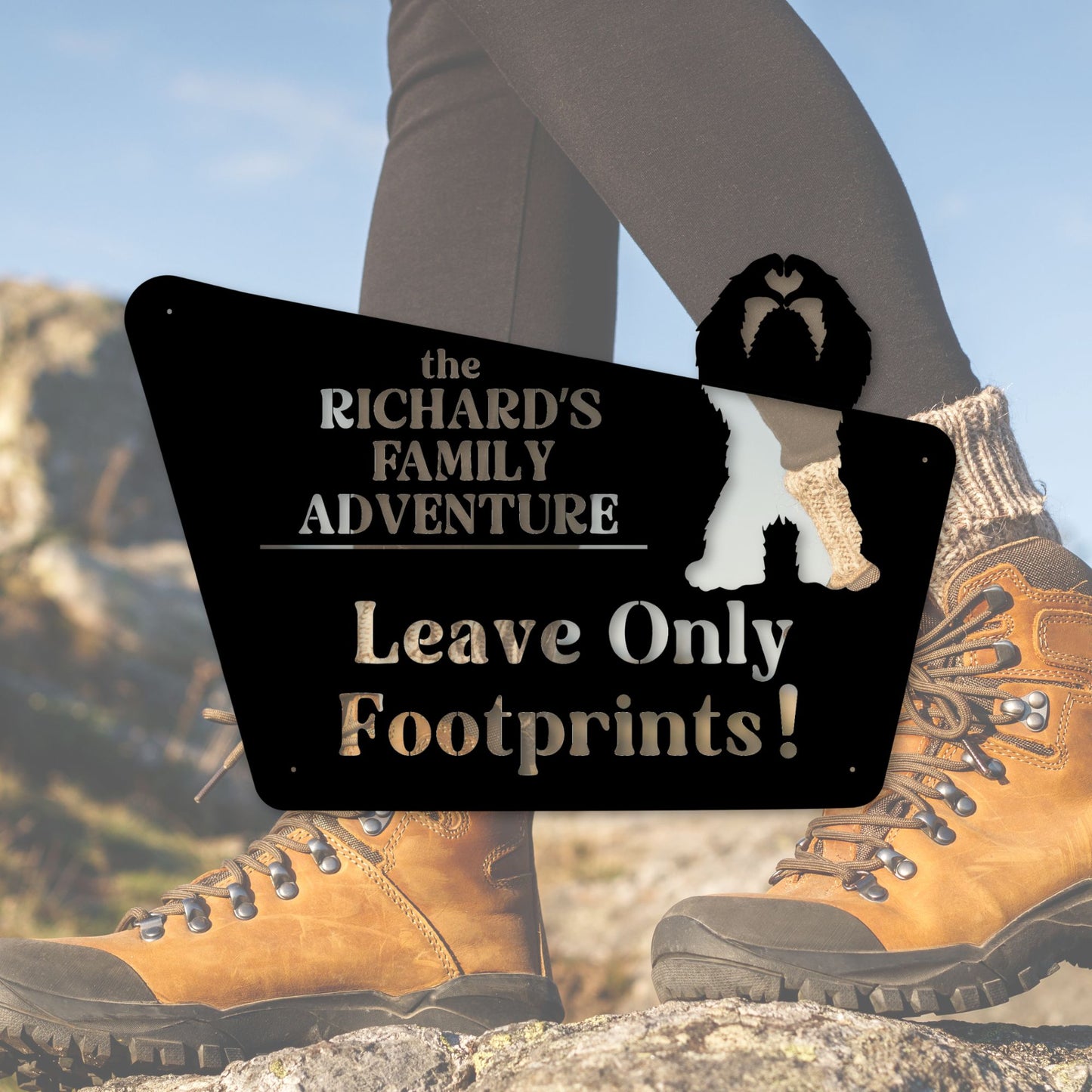 Hiking boots with a sign reading 'the RICHARD'S FAMILY ADVENTURE Leave Only Footprints!' against a natural background.