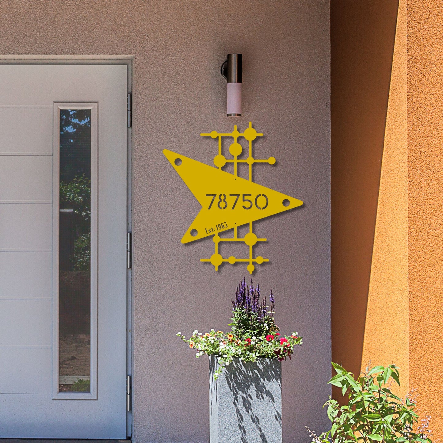 Yellow geometric design with numbers on a building exterior, next to a door and planters.
