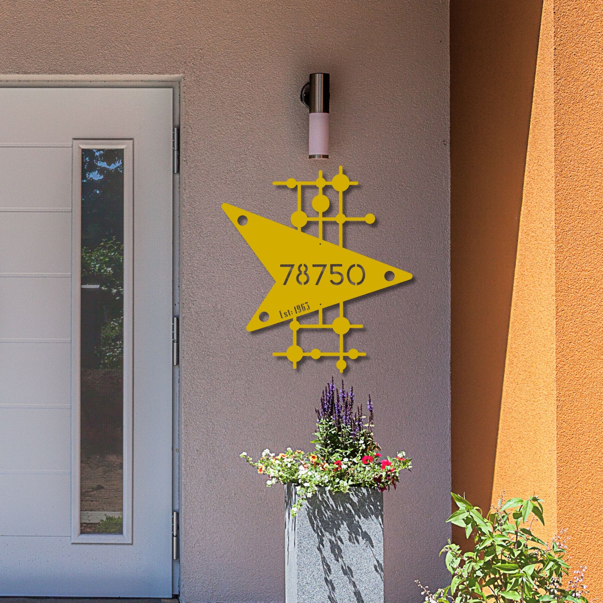 Yellow geometric design with numbers on a building exterior, next to a door and planters.