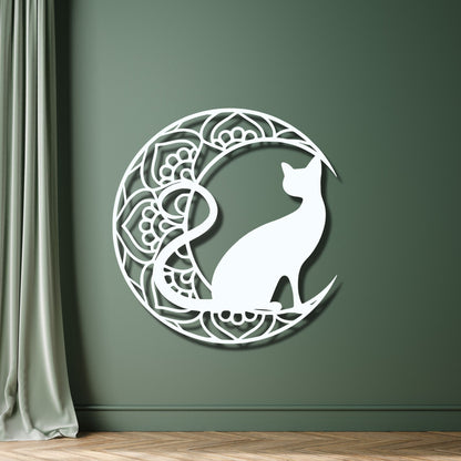 Decorative wall art of a cat on a crescent moon with mandala patterns against a green wall.