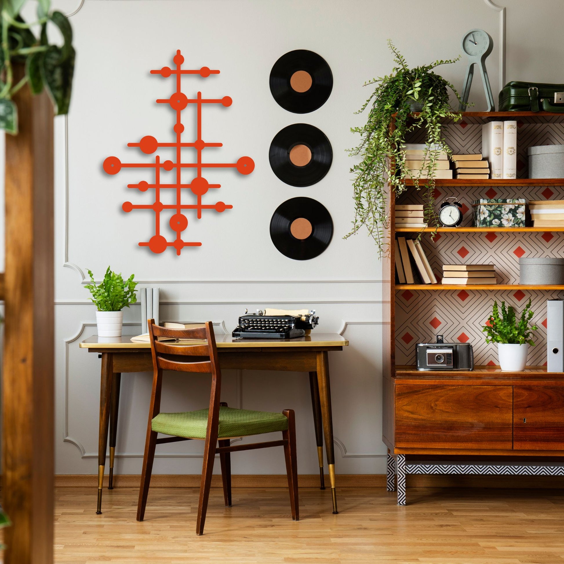 Home office with wooden desk, chair, and bookshelf with decorative items.