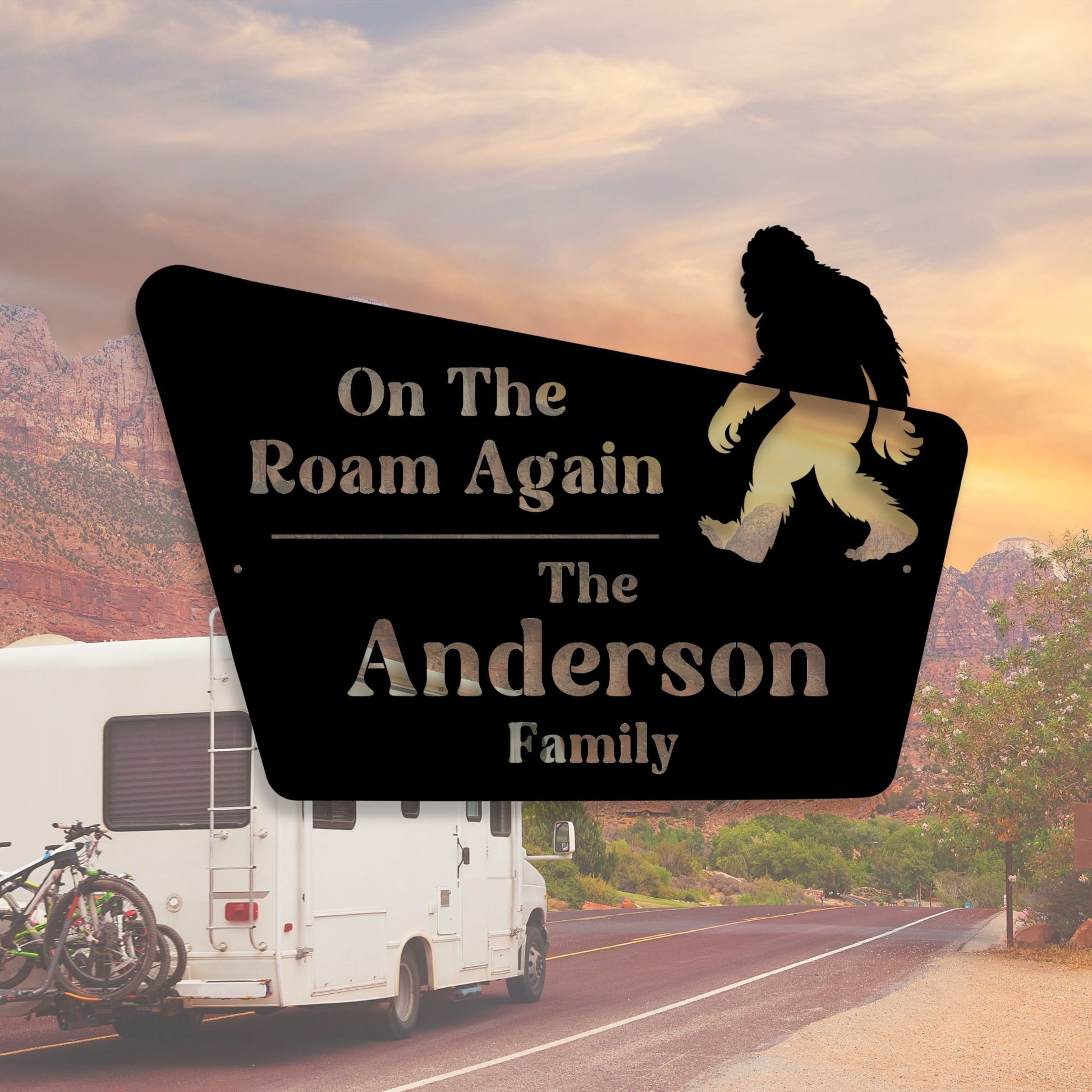 Personalized sign with 'On The Roam Again' and 'The Anderson Family' text, with a silhouette of a person and Bigfoot, set against a scenic road with an RV and bicycles.