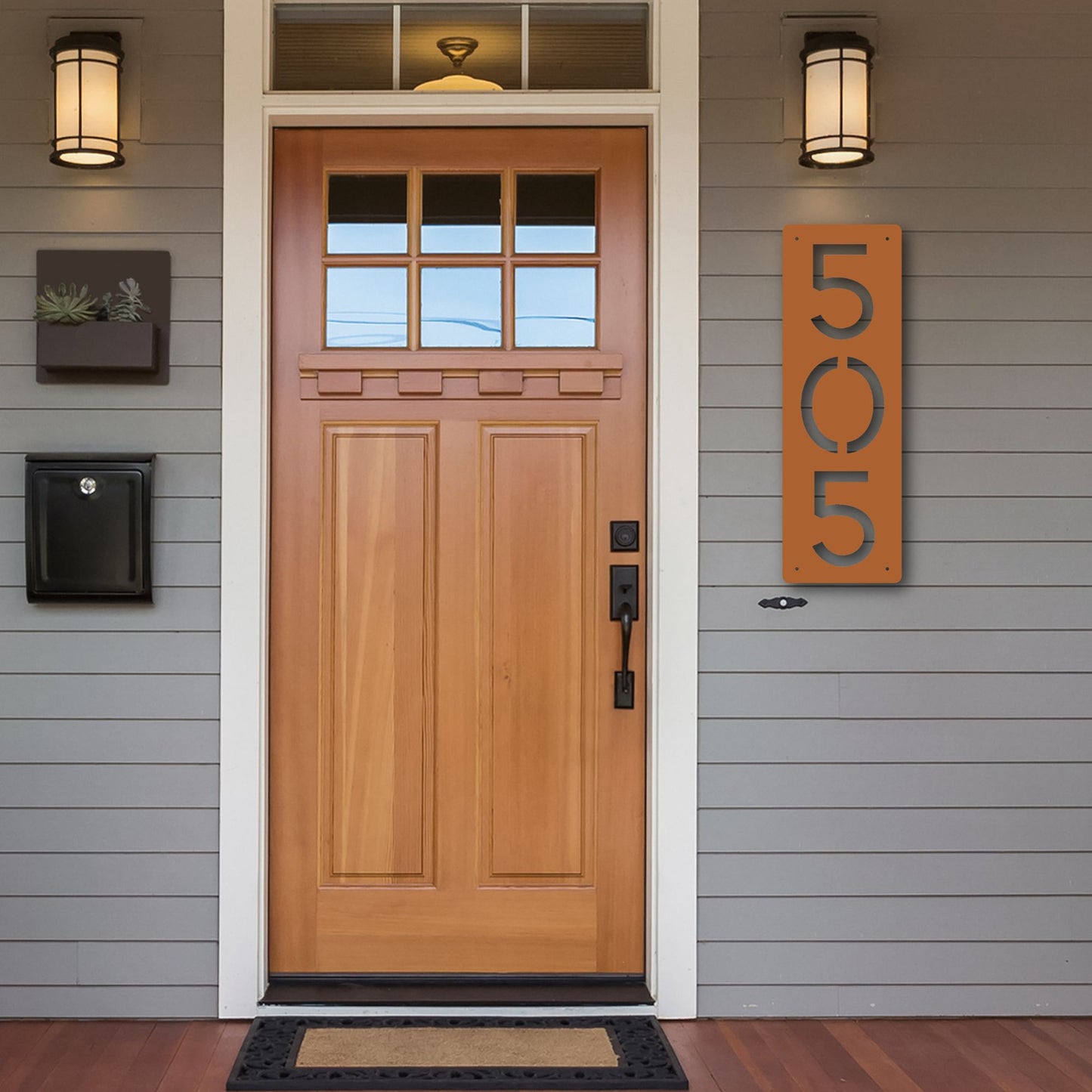 Wooden front door with house numbers on a gray siding home