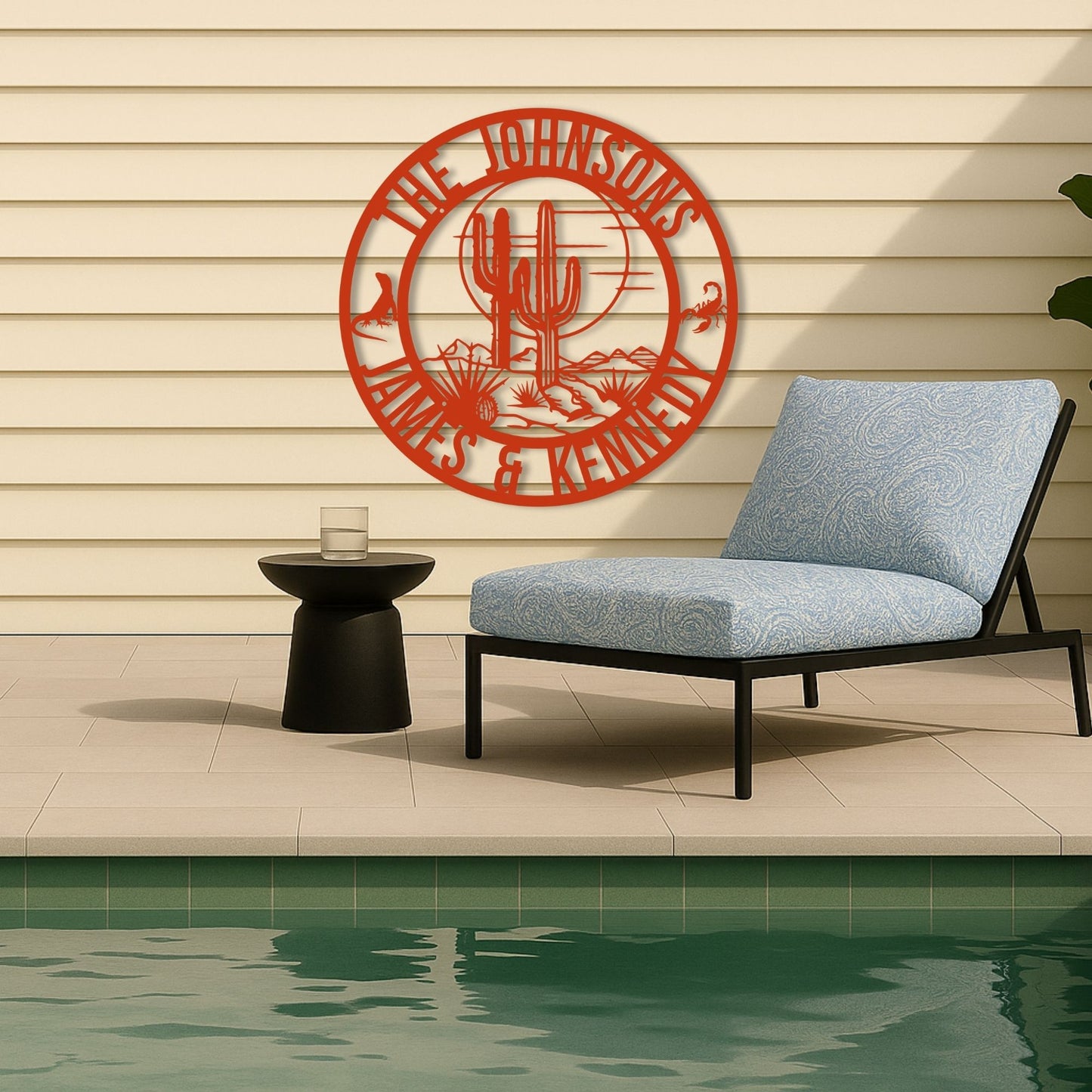 Decorative wall art with 'The Johnsons' design above a lounge chair by a pool.