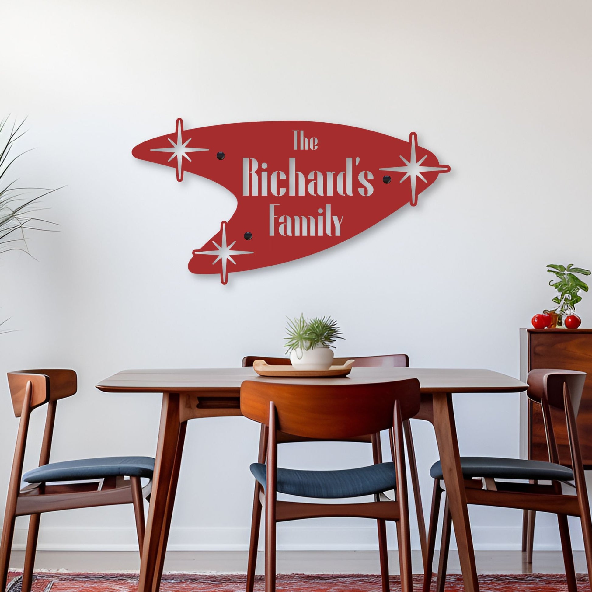 Dining room with a red family name wall art above a wooden table and chairs.
