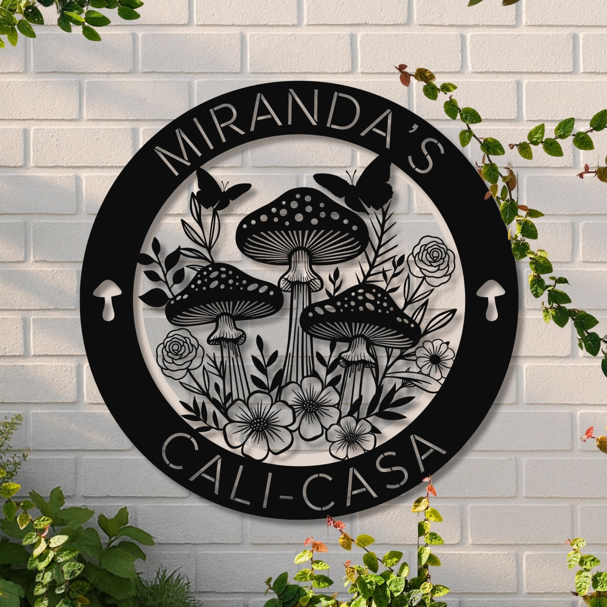 Decorative wall art with mushrooms and flowers on a white brick wall.