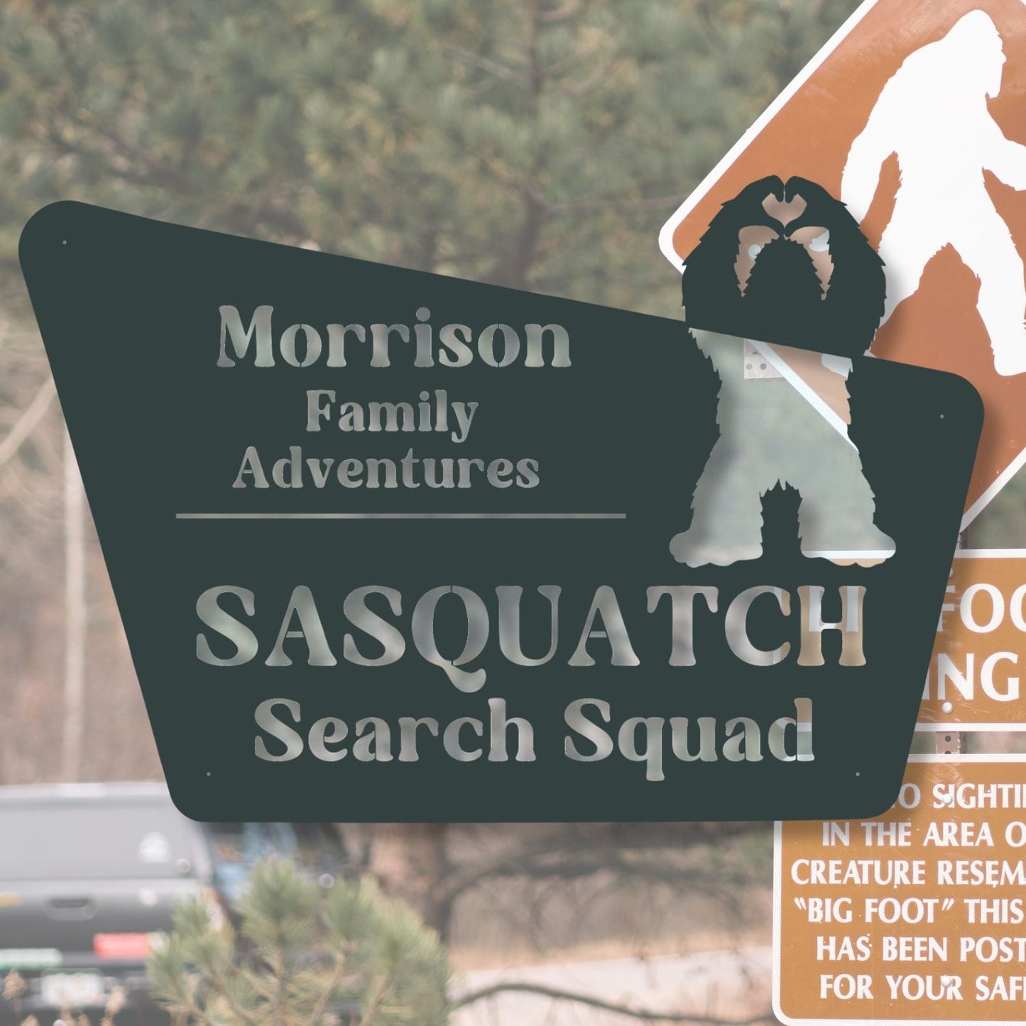 Sasquatch search squad sign with a blurred background of a road and vehicle.