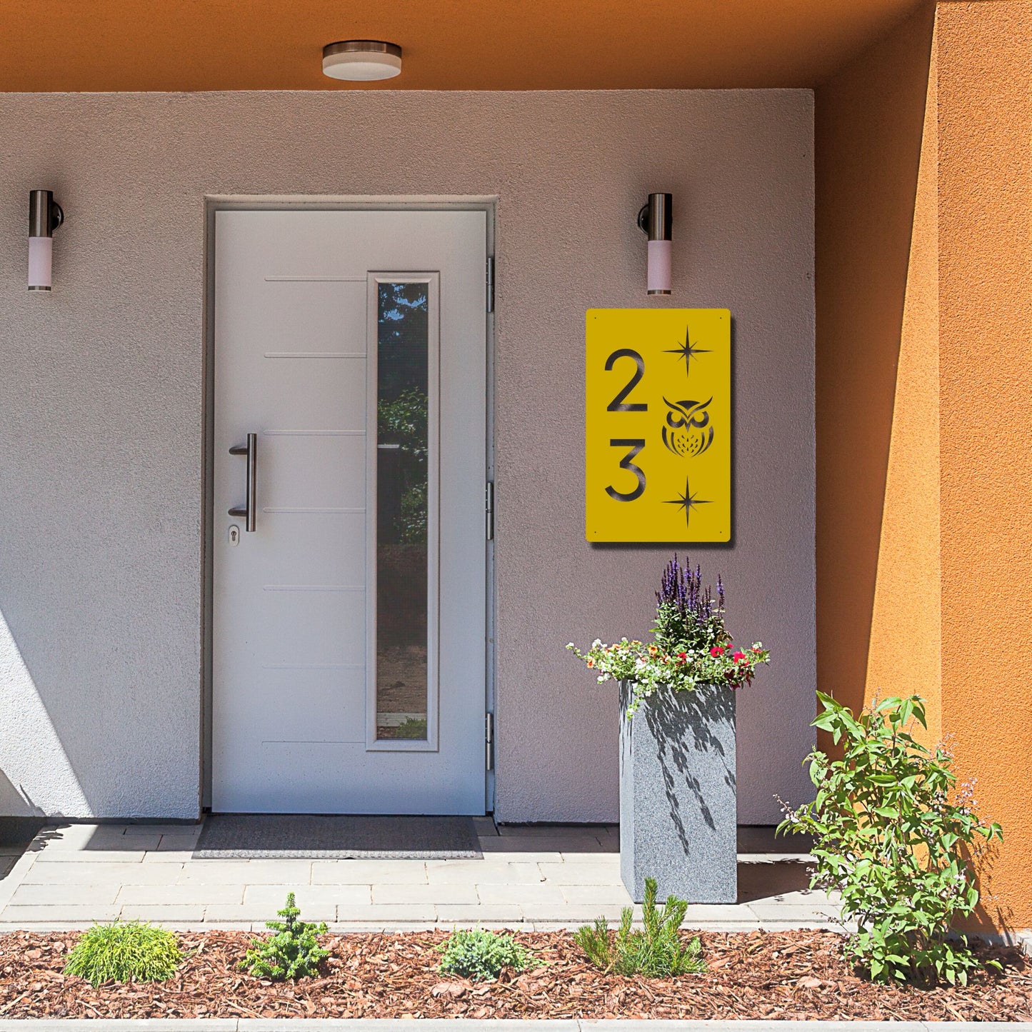 Modern house entrance with a yellow house number sign and plants.