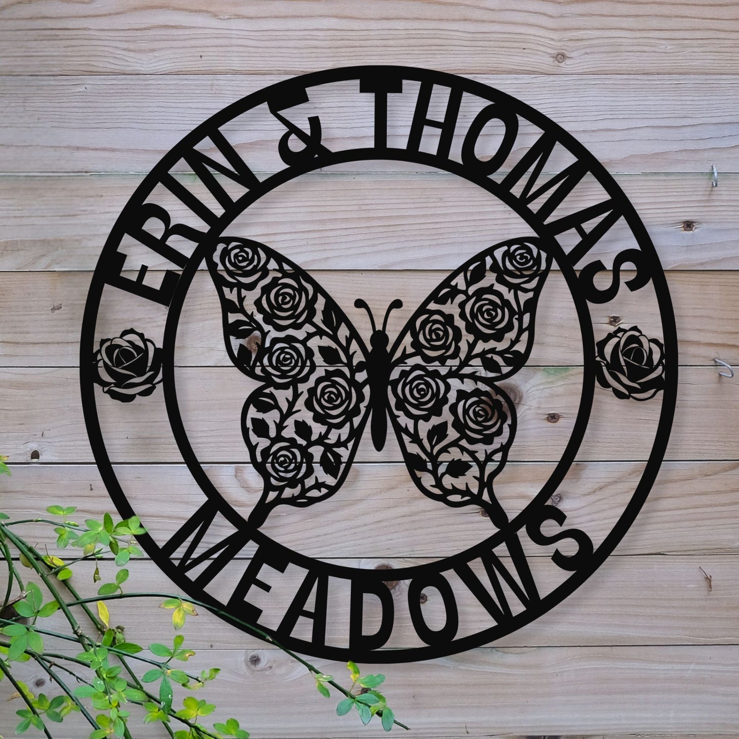 Decorative metal sign with butterfly and floral design on a wooden background