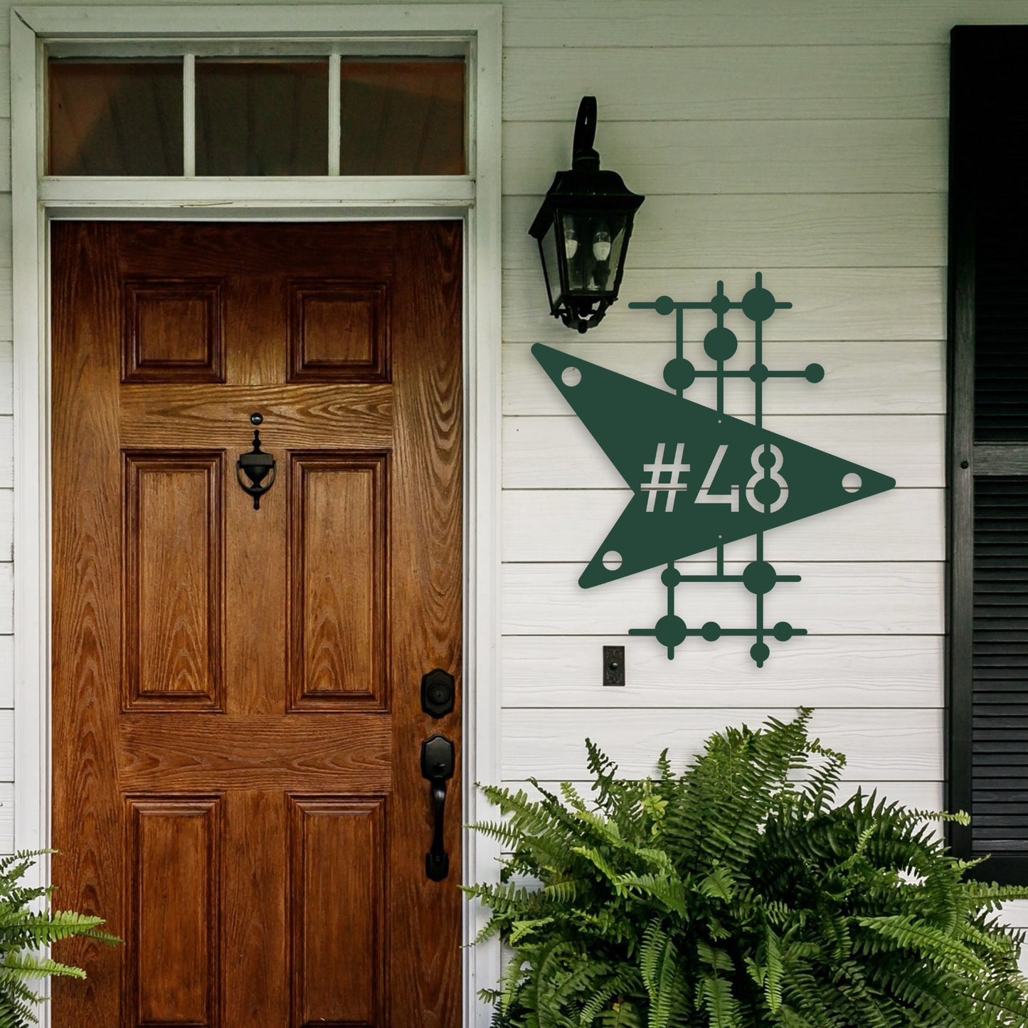 Wooden front door with decorative green sign on a white wall