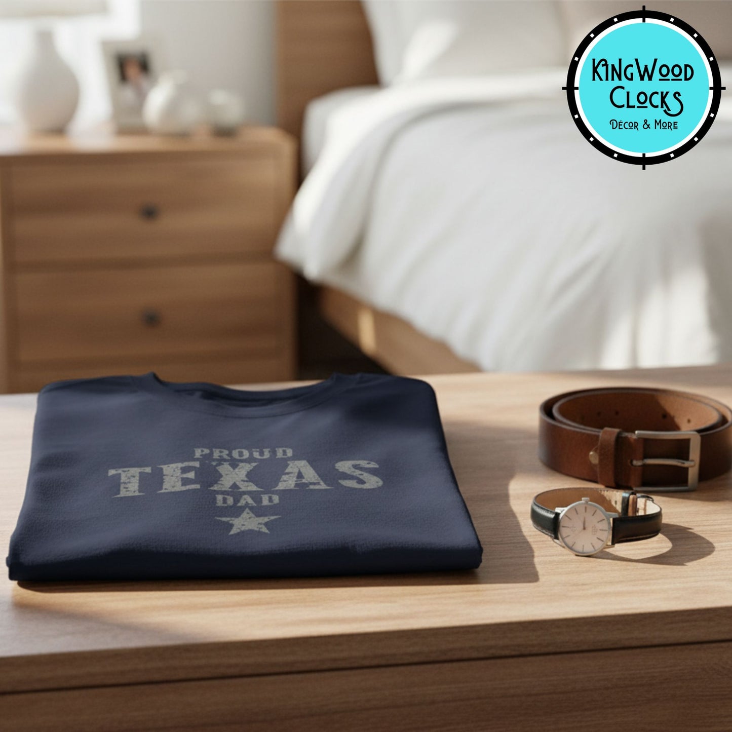 Navy blue sweatshirt with 'Proud Texas Dad' text on a wooden surface, with a bed and nightstand in the background.