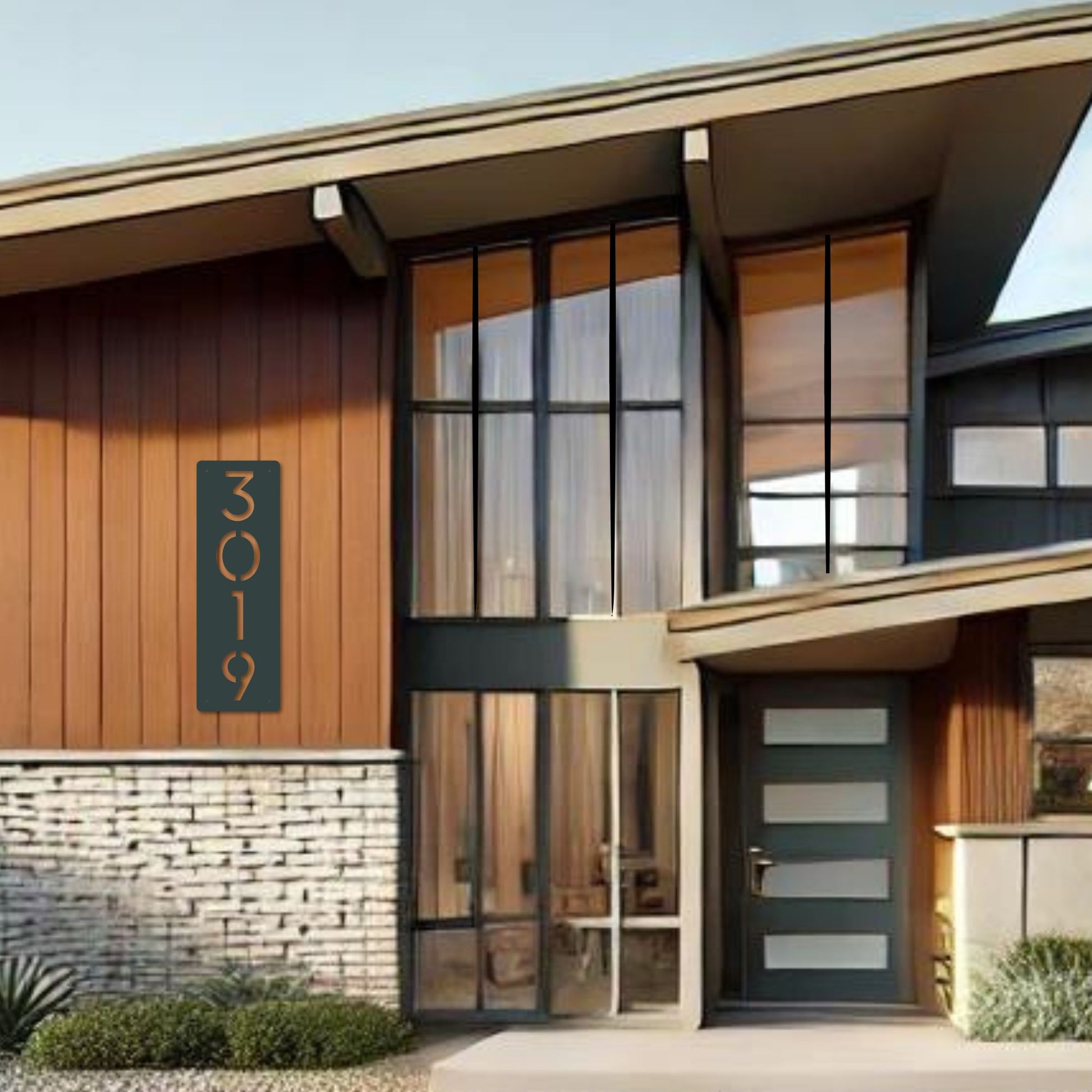 Modern house exterior with glass doors and a street number sign.